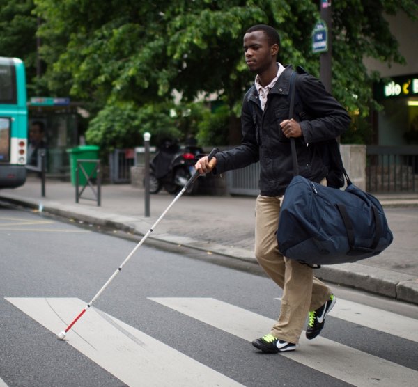 A blind man crossing the street at a crosswalk